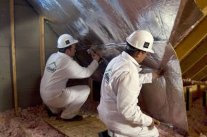 Technicians installing radiant barrier in attic