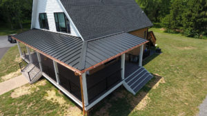 aerial view of house with wrap-around porch and both metal and asphalt roofing