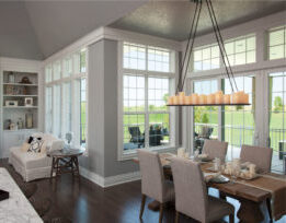 Open neutral-toned dining room and living room with windows all along the walls