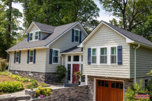 Home in woods with yellow siding and new asphalt shingle roof